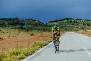 voll Länge Porträt von ein aktiv Triathlet im Sportbekleidung und mit ein schützend Helm Reiten ein Fahrrad. selektiv Fokus foto