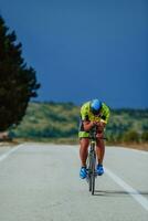 voll Länge Porträt von ein aktiv Triathlet im Sportbekleidung und mit ein schützend Helm Reiten ein Fahrrad. selektiv Fokus foto