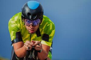 voll Länge Porträt von ein aktiv Triathlet im Sportbekleidung und mit ein schützend Helm Reiten ein Fahrrad. selektiv Fokus foto