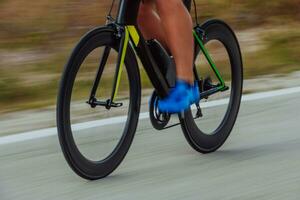 schließen oben Foto von ein aktiv Triathlet im Sportbekleidung und mit ein schützend Helm Reiten ein Fahrrad. selektiv Fokus