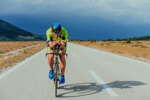 voll Länge Porträt von ein aktiv Triathlet im Sportbekleidung und mit ein schützend Helm Reiten ein Fahrrad. selektiv Fokus foto