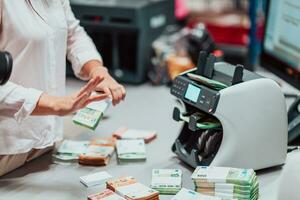 Bank Angestellte mit Geld Zählen Maschine während Sortierung und Zählen Papier Banknoten Innerhalb Bank Gewölbe. groß Beträge von Geld im das Bank foto