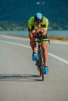 voll Länge Porträt von ein aktiv Triathlet im Sportbekleidung und mit ein schützend Helm Reiten ein Fahrrad. selektiv Fokus foto