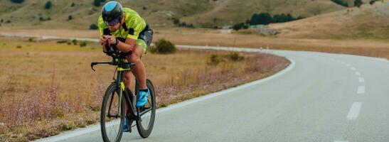 voll Länge Porträt von ein aktiv Triathlet im Sportbekleidung und mit ein schützend Helm Reiten ein Fahrrad. selektiv Fokus foto