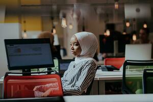 Geschäft Bildung und Büro Konzept. afrikanisch amerikanisch Geschäftsfrau tragen ein Hijab Arbeiten, Tippen auf ein Computer. weiblich Unternehmer Sitzung auf ihr Schreibtisch. foto