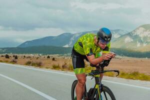 voll Länge Porträt von ein aktiv Triathlet im Sportbekleidung und mit ein schützend Helm Reiten ein Fahrrad. selektiv Fokus foto