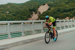 voll Länge Porträt von ein aktiv Triathlet im Sportbekleidung und mit ein schützend Helm Reiten ein Fahrrad. selektiv Fokus foto