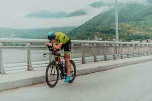 voll Länge Porträt von ein aktiv Triathlet im Sportbekleidung und mit ein schützend Helm Reiten ein Fahrrad. selektiv Fokus foto