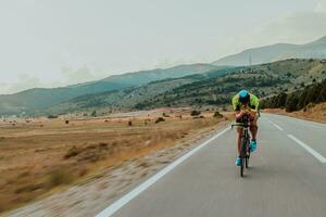 voll Länge Porträt von ein aktiv Triathlet im Sportbekleidung und mit ein schützend Helm Reiten ein Fahrrad. selektiv Fokus foto