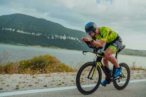 voll Länge Porträt von ein aktiv Triathlet im Sportbekleidung und mit ein schützend Helm Reiten ein Fahrrad. selektiv Fokus foto