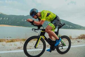 voll Länge Porträt von ein aktiv Triathlet im Sportbekleidung und mit ein schützend Helm Reiten ein Fahrrad. selektiv Fokus foto