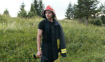 Feuerwehrmann mit Uniform und Helm Stand im Vorderseite von elektrisch Draht auf ein Dach oben foto