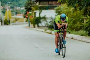 voll Länge Porträt von ein aktiv Triathlet im Sportbekleidung und mit ein schützend Helm Reiten ein Fahrrad. selektiv Fokus foto