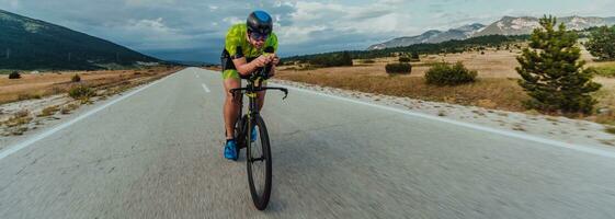 voll Länge Porträt von ein aktiv Triathlet im Sportbekleidung und mit ein schützend Helm Reiten ein Fahrrad. selektiv Fokus foto