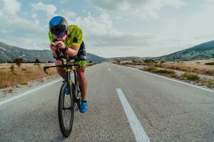 voll Länge Porträt von ein aktiv Triathlet im Sportbekleidung und mit ein schützend Helm Reiten ein Fahrrad. selektiv Fokus foto