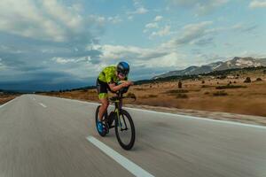 voll Länge Porträt von ein aktiv Triathlet im Sportbekleidung und mit ein schützend Helm Reiten ein Fahrrad. selektiv Fokus foto