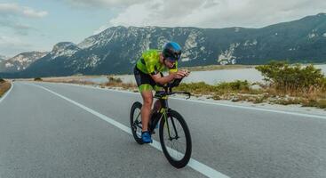 voll Länge Porträt von ein aktiv Triathlet im Sportbekleidung und mit ein schützend Helm Reiten ein Fahrrad. selektiv Fokus foto