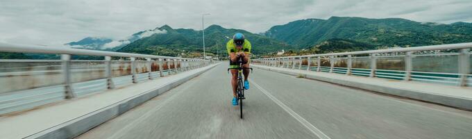 voll Länge Porträt von ein aktiv Triathlet im Sportbekleidung und mit ein schützend Helm Reiten ein Fahrrad. selektiv Fokus foto