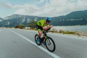 voll Länge Porträt von ein aktiv Triathlet im Sportbekleidung und mit ein schützend Helm Reiten ein Fahrrad. selektiv Fokus foto