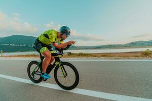 voll Länge Porträt von ein aktiv Triathlet im Sportbekleidung und mit ein schützend Helm Reiten ein Fahrrad. selektiv Fokus foto