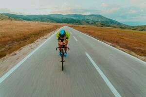 voll Länge Porträt von ein aktiv Triathlet im Sportbekleidung und mit ein schützend Helm Reiten ein Fahrrad. selektiv Fokus foto