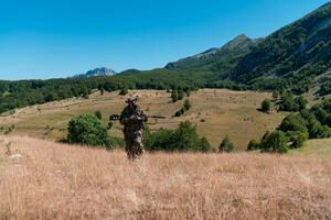 Heer Soldat halten ein Scharfschütze Gewehr mit Umfang und Gehen im das Wald. Krieg, Armee, Technologie und Menschen Konzept. foto