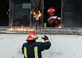 Feuerwehrmann Held Tragen Baby Mädchen aus von Verbrennung Gebäude Bereich von Feuer Vorfall. Rettung Menschen von gefährlich Platz foto