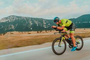 voll Länge Porträt von ein aktiv Triathlet im Sportbekleidung und mit ein schützend Helm Reiten ein Fahrrad. selektiv Fokus foto