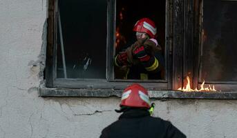 Feuerwehrmann Held Tragen Baby Mädchen aus von Verbrennung Gebäude Bereich von Feuer Vorfall. Rettung Menschen von gefährlich Platz foto