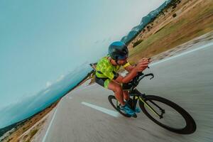 voll Länge Porträt von ein aktiv Triathlet im Sportbekleidung und mit ein schützend Helm Reiten ein Fahrrad. selektiv Fokus foto