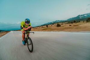 voll Länge Porträt von ein aktiv Triathlet im Sportbekleidung und mit ein schützend Helm Reiten ein Fahrrad. selektiv Fokus foto