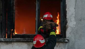 Feuerwehrmann Held Tragen Baby Mädchen aus von Verbrennung Gebäude Bereich von Feuer Vorfall. Rettung Menschen von gefährlich Platz foto