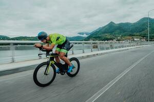 voll Länge Porträt von ein aktiv Triathlet im Sportbekleidung und mit ein schützend Helm Reiten ein Fahrrad. selektiv Fokus foto