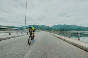 voll Länge Porträt von ein aktiv Triathlet im Sportbekleidung und mit ein schützend Helm Reiten ein Fahrrad. selektiv Fokus foto