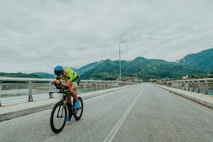 voll Länge Porträt von ein aktiv Triathlet im Sportbekleidung und mit ein schützend Helm Reiten ein Fahrrad. selektiv Fokus foto