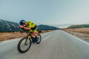 voll Länge Porträt von ein aktiv Triathlet im Sportbekleidung und mit ein schützend Helm Reiten ein Fahrrad. selektiv Fokus foto