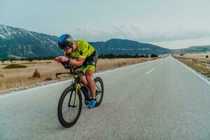 voll Länge Porträt von ein aktiv Triathlet im Sportbekleidung und mit ein schützend Helm Reiten ein Fahrrad. selektiv Fokus foto