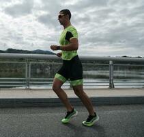 Triathlonsportler, der auf der Straße läuft foto