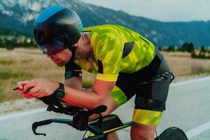 voll Länge Porträt von ein aktiv Triathlet im Sportbekleidung und mit ein schützend Helm Reiten ein Fahrrad. selektiv Fokus foto