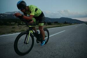 Triathlon-Athlet, der nachts Fahrrad fährt foto