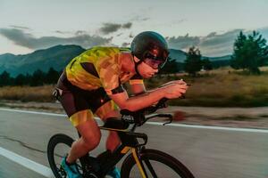 Nacht Antrieb. voll Länge Porträt von ein aktiv Triathlet im Sportbekleidung und mit ein schützend Helm Reiten ein Fahrrad im Nacht Zeit.. selektiv Fokus foto