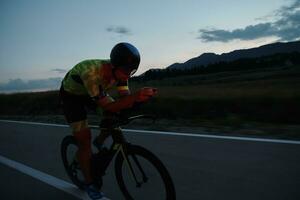 Triathlon-Athlet, der nachts Fahrrad fährt foto