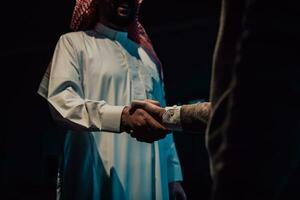 ein Alten arabisch Mann zittern Hände mit ein Geschäftsmann und Ende ein Geschäft Treffen mit erfolgreich Geschäft Angebote foto