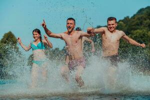 ein Gruppe von vielfältig jung Menschen haben Spaß zusammen wie Sie Lauf entlang das Fluss und abspielen Wasser Spiele foto