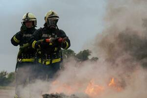 Feuerwehrleute Kampf das Feuer Flamme zu Steuerung Feuer nicht zu Verbreitung aus. Feuerwehrmann industriell und Öffentlichkeit Sicherheit Konzept. der Verkehr oder Auto Unfall Rettung und Hilfe Aktion. foto