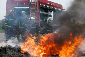 Feuerwehrleute Kampf das Feuer Flamme zu Steuerung Feuer nicht zu Verbreitung aus. Feuerwehrmann industriell und Öffentlichkeit Sicherheit Konzept. der Verkehr oder Auto Unfall Rettung und Hilfe Aktion. foto