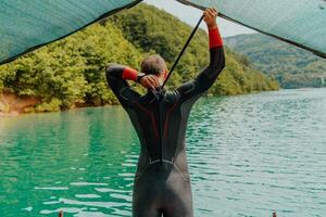 Athlet Putten auf ein Schwimmen passen und vorbereiten zum Triathlon Schwimmen und Ausbildung im das Fluss umgeben durch natürlich Grün foto