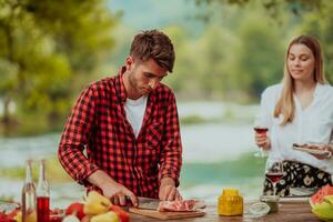 ein Mann vorbereiten ein köstlich Abendessen zum seine freunde Wer sind haben Spaß durch das Fluss im Natur foto