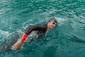 ein Triathlet im ein Fachmann Schwimmen passen Züge auf das Fluss während vorbereiten zum olympisch Schwimmen foto