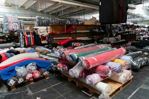 Innere von ein industriell Warenhaus mit Stoff Rollen Proben. klein Geschäft Textil- bunt Lagerhaus. foto